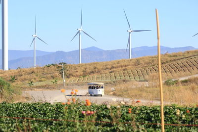 Wind turbines on field against sky