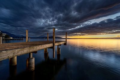 Pier over lake against sky during sunset