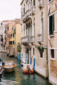 Boats moored in canal amidst buildings in city