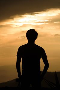 Silhouette man standing against orange sky