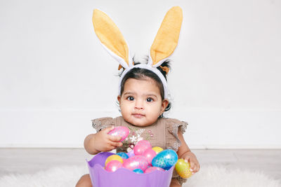 Portrait of cute girl playing with toy against wall