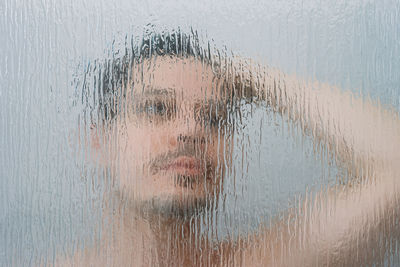 Portrait of man behind shower door