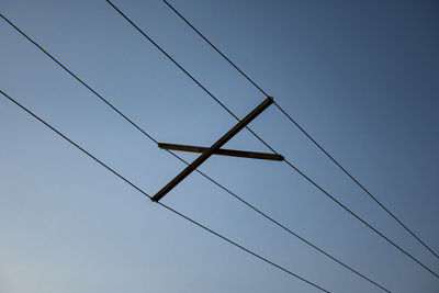 Low angle view of power lines against clear blue sky