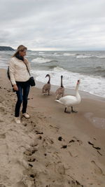 Full length of woman on beach with ducks