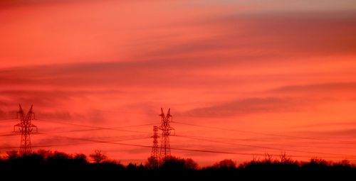 Low angle view of silhouette electricity pylon against romantic sky