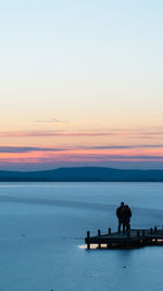 Silhouette woman standing on beach against sky during sunset