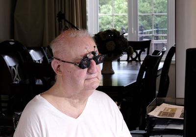 Portrait of man sitting on window at home