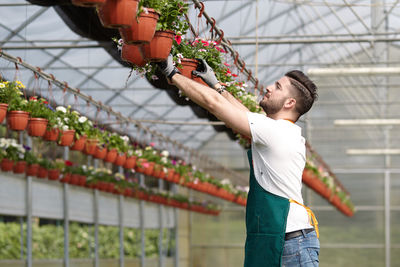 Side view of young man standing in greenhouse