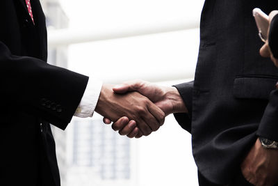 Midsection of business people shaking hands