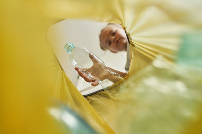 Girl throwing plastic bottle in garbage bag