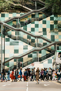 People walking on street by modern buildings in city