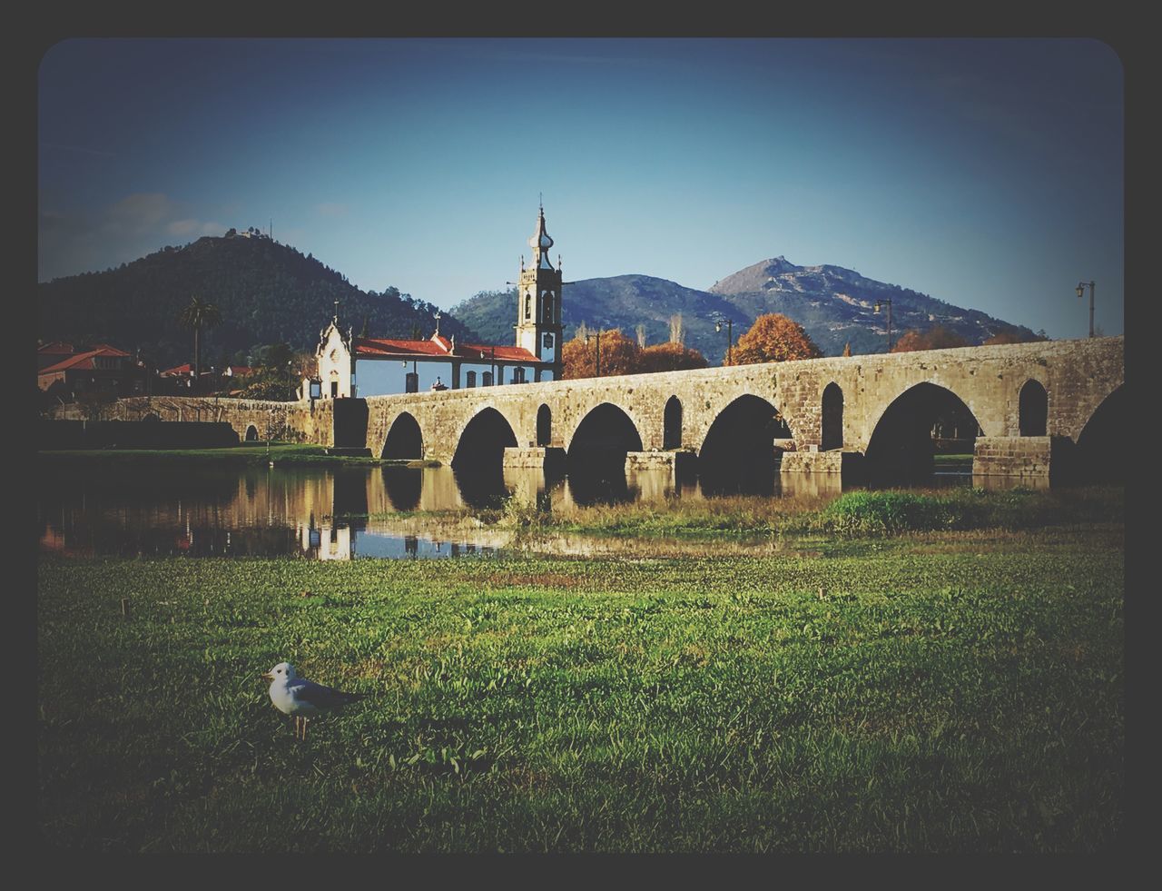 architecture, built structure, transfer print, clear sky, arch, building exterior, auto post production filter, connection, grass, bridge - man made structure, sky, history, copy space, blue, mountain, bridge, outdoors, day, no people, sunlight