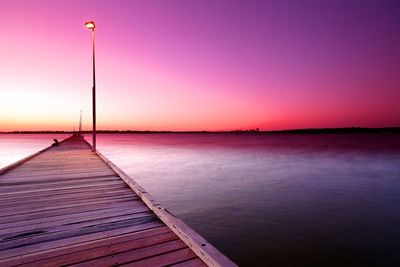 Pier over sea against sky during sunset