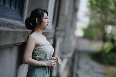 Young woman standing against trees