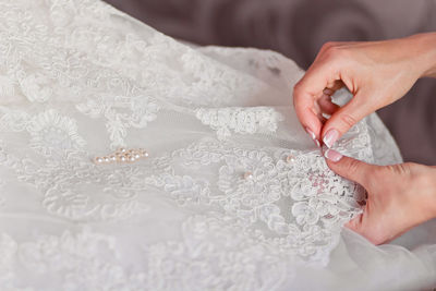 Cropped hand of woman sewing white fabric