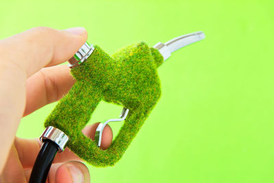 Close-up of hand holding leaf over green background