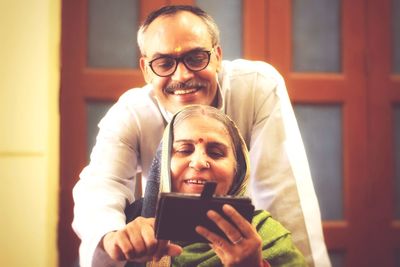 Portrait of senior couple using mobile phone at home