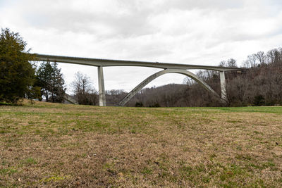 Arch bridge on field against sky