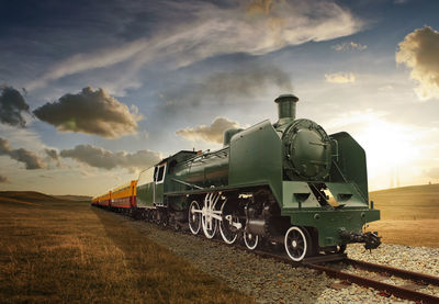 Train on railroad tracks against sky during sunset