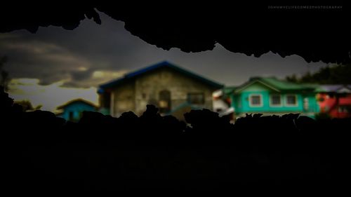 Silhouette houses against sky at night