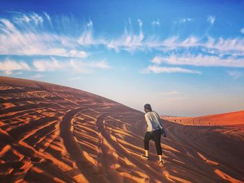 Woman walking on desert against sky