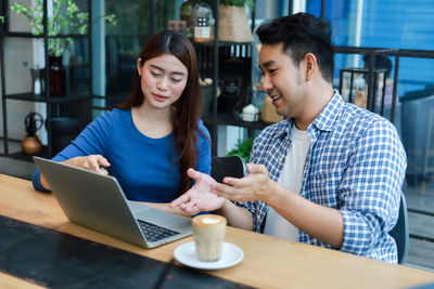 Young woman using phone while sitting on table