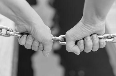 Close-up of hands holding chain
