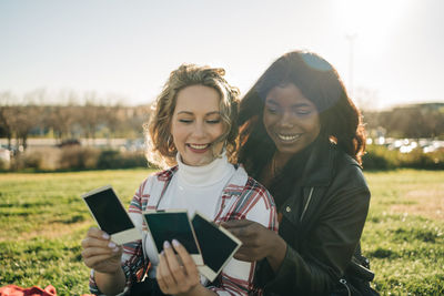 Portrait of smiling young woman using smart phone against sky