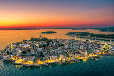 High angle view of townscape by sea against sky during sunset