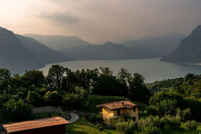 Houses by lake and mountains against sky