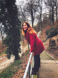 Portrait of smiling young woman standing against trees