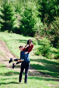 Full length of boyfriend carrying girlfriend in forest