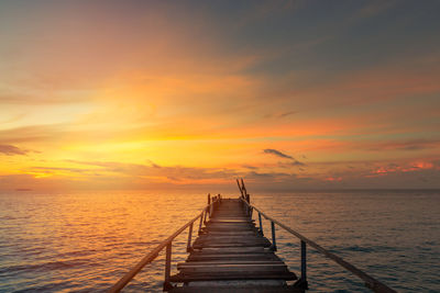 Pier over sea against sky during sunset