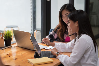 Woman using phone while sitting on table