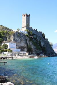 Built structure by sea against clear blue sky