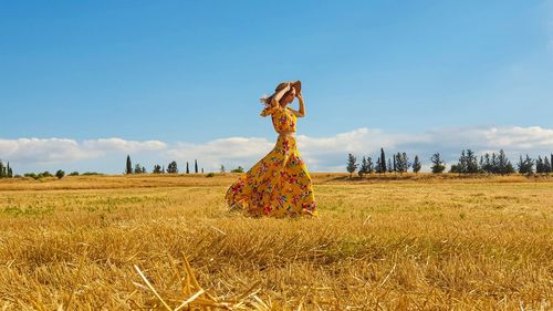 Woman standing on field against sky