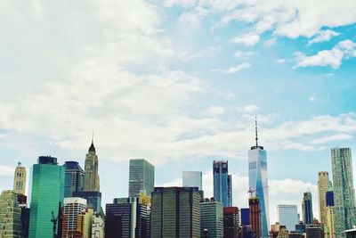 Low angle view of skyscrapers against cloudy sky