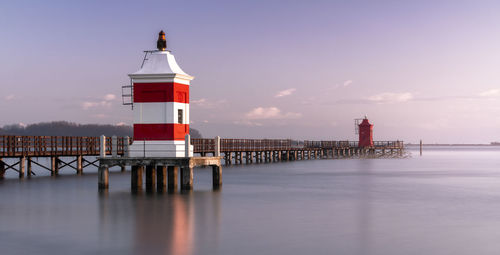 Lighthouse by sea against sky