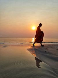 Man on beach against sky during sunset
