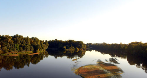 Reflection of trees in lake against clear sky