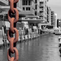 Close-up of chain by river against buildings in city