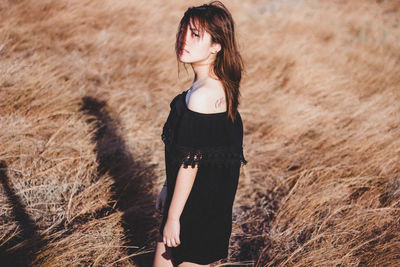 Portrait of young woman standing on field