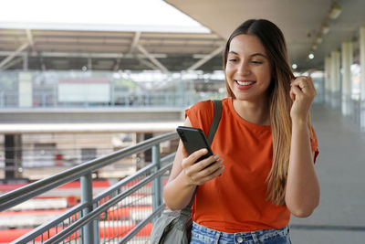 Brazilian young woman walking in train station watching her mobile phone in sao paulo, brazil