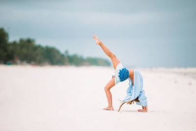 Midsection of man with arms raised on beach