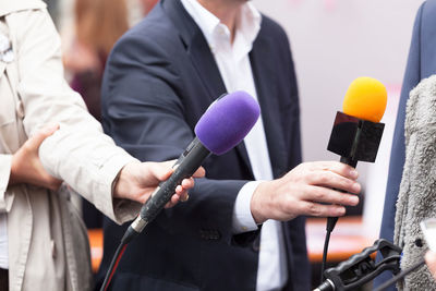 Cropped hand of reporter holding microphone