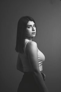 Portrait of young woman looking away against wall