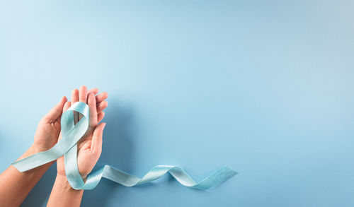 Midsection of woman holding blue over white background