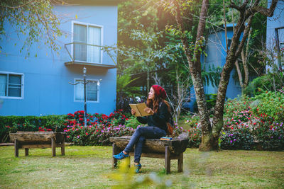 Woman sitting on bench against plants