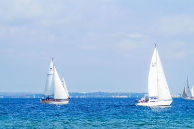 Sailboats sailing on blue sea against sky