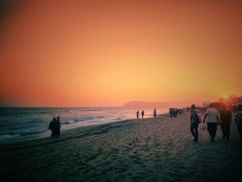 Silhouette people on beach against sky during sunset